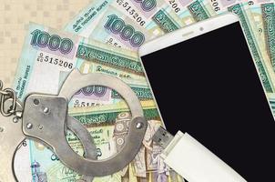 1000 Sri Lankan rupees bills and smartphone with police handcuffs. Concept of hackers phishing attacks, illegal scam or malware soft distribution photo