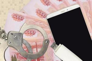 5000 russian rubles bills and smartphone with police handcuffs. Concept of hackers phishing attacks, illegal scam or malware soft distribution photo