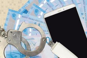 2000 russian rubles bills and smartphone with police handcuffs. Concept of hackers phishing attacks, illegal scam or malware soft distribution photo