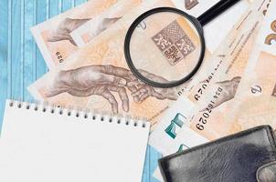 200 Czech korun bills and magnifying glass with black purse and notepad. Concept of counterfeit money. Search for differences in details on money bills to detect fake photo