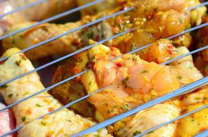 Marinated chicken legs on hot BBQ charcoal field grill photo