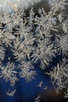Snowflakes frost rime macro on window glass pane photo