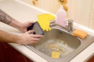 The landlord uses the tablet to call a cleaner in order to clean the clogged kitchen sink photo