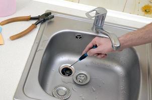 Close-up of handsome plumber hands repairing drain of kitchen sink photo