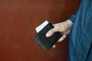 Man holds in hands black leather wallet with ukrainian money or thief who stole wallet full of money photo