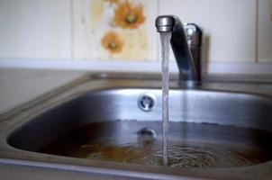 tapón del fregadero de acero inoxidable cerca del orificio lleno de agua y partículas de comida foto