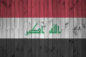 Iraq flag depicted in bright paint colors on old wooden wall. Textured banner on rough background photo