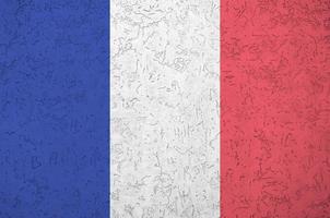 France flag depicted in bright paint colors on old relief plastering wall. Textured banner on rough background photo