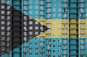 bandera de bahamas representada en colores de pintura en un edificio residencial de varios pisos en construcción. banner texturizado sobre fondo de pared de ladrillo foto