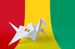 Guinea flag depicted on paper origami crane wing. Handmade arts concept photo