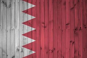 Bahrain flag depicted in bright paint colors on old wooden wall. Textured banner on rough background photo