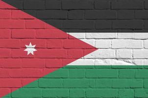 bandera jordana representada en colores de pintura en la pared de ladrillo antiguo. banner texturizado sobre fondo de mampostería de pared de ladrillo grande foto