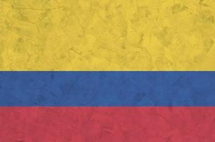 Colombia flag depicted in bright paint colors on old relief plastering wall. Textured banner on rough background photo