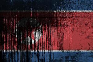 North Korea flag depicted in paint colors on old and dirty oil barrel wall closeup. Textured banner on rough background photo