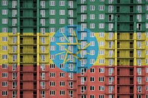 Ethiopia flag depicted in paint colors on multi-storey residental building under construction. Textured banner on brick wall background photo