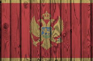 bandera de montenegro representada en colores de pintura brillante en la pared de madera vieja. banner texturizado sobre fondo áspero foto