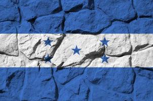 Honduras flag depicted in paint colors on old stone wall closeup. Textured banner on rock wall background photo