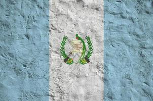 Guatemala flag depicted in bright paint colors on old relief plastering wall. Textured banner on rough background photo