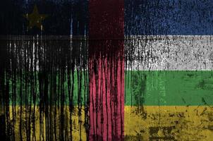 Central African Republic flag depicted in paint colors on old and dirty oil barrel wall closeup. Textured banner on rough background photo