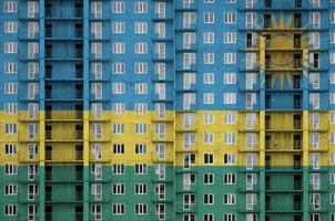 bandera de ruanda representada en colores de pintura en un edificio residencial de varios pisos en construcción. banner texturizado sobre fondo de pared de ladrillo foto