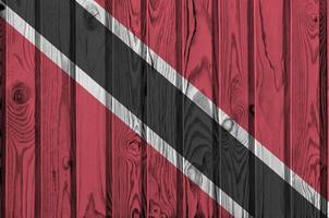 Trinidad and Tobago flag depicted in bright paint colors on old wooden wall. Textured banner on rough background photo