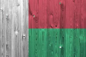 Madagascar flag depicted in bright paint colors on old wooden wall. Textured banner on rough background photo