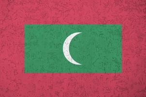 Maldives flag depicted in bright paint colors on old relief plastering wall. Textured banner on rough background photo