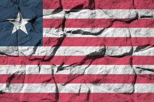 Liberia flag depicted in paint colors on old stone wall closeup. Textured banner on rock wall background photo