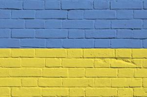 Ukraine flag depicted in paint colors on old brick wall. Textured banner on big brick wall masonry background photo