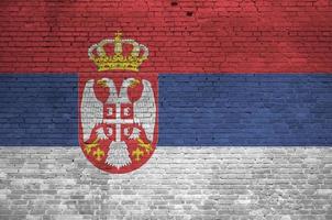 bandera de serbia representada en colores de pintura en la pared de ladrillo antiguo. banner texturizado sobre fondo de mampostería de pared de ladrillo grande foto