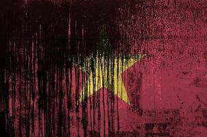 Vietnam flag depicted in paint colors on old and dirty oil barrel wall closeup. Textured banner on rough background photo