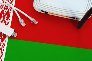 Belarus flag depicted on table with internet rj45 cable, wireless usb wifi adapter and router. Internet connection concept photo