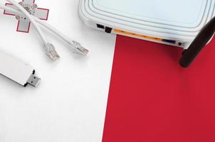 Malta flag depicted on table with internet rj45 cable, wireless usb wifi adapter and router. Internet connection concept photo