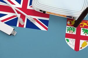 Fiji flag depicted on table with internet rj45 cable, wireless usb wifi adapter and router. Internet connection concept photo