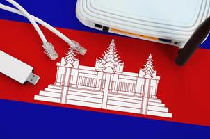 Cambodia flag depicted on table with internet rj45 cable, wireless usb wifi adapter and router. Internet connection concept photo