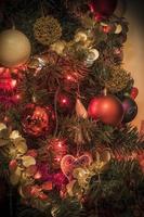 A closeup of ornaments on a Christmas tree in red tones photo