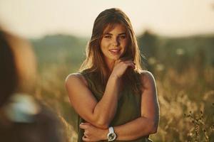 retrato de una chica feliz parada en el campo iluminada por la luz del sol foto