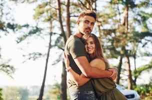 felices juntos. abrazándose unos a otros. hermosa pareja joven diviértete en el bosque durante el día foto