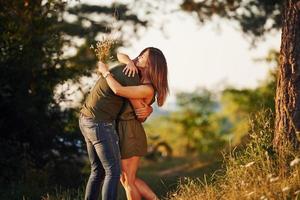 Lovely people embracing each other. Beautiful young couple have a good time in the forest at daytime photo