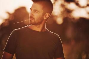 Confident man standing in the field illuminated by sunlight photo