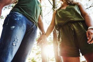 vista desde abajo. árboles altos hermosa pareja joven diviértete en el bosque durante el día foto