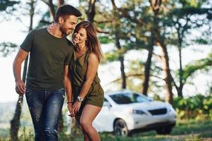 dando un paseo coche detrás. hermosa pareja joven diviértete en el bosque durante el día foto