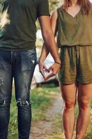 Making heart and love gesture by the hands. Young couple have a good time in the forest at daytime photo