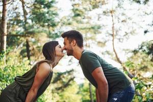 Side view. Beautiful young couple have a good time in the forest at daytime photo