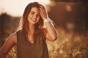 retrato de una chica feliz parada en el campo iluminada por la luz del sol foto