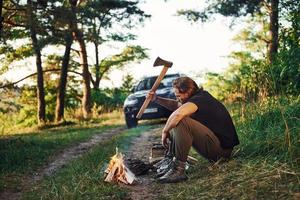 Time for a rest. Man in black shirt near the campfire in the forest at his weekend time photo