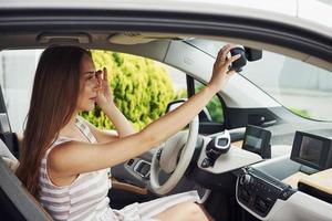 vista lateral. mujer conductora dentro de un automóvil moderno. probando auto nuevo foto