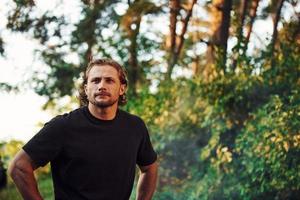 retrato de hombre que se para en el bosque y mira la naturaleza. automóvil estacionado detrás foto