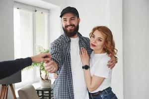 Here's your keys. Happy couple together in their new house. Conception of moving photo