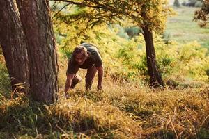 Tired traveler on the hill. Beautiful man in the forest. Good weather. Beautiful orange colored sunlight photo